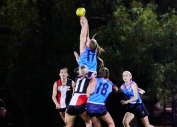 Two AFL players watching the ball